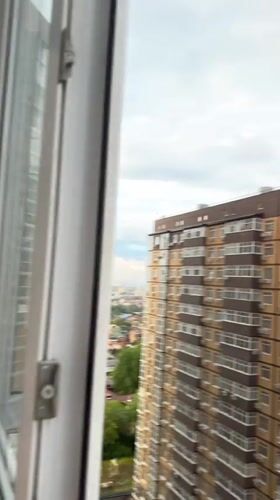 Woman watches rainbow from apartment window in Ovoshchnoy, Russia