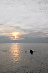 Small boat crosses calm waters at sunset near Lhokseumawe