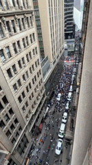 Large crowd and vehicle procession fill Manhattan street mid-morning