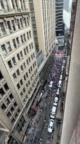 Large crowd and vehicle procession fill Manhattan street mid-morning