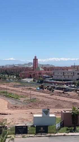 Marrakesh cityscape with pink mosque, mountains captured on video