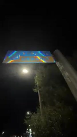 At night, a camera pivots upward, past a border sign for Ukraine, and pans down to a row of tour buses and other vehicles parked on a road. The foreground includes a silver minivan, and the buses are orange and white. People can be seen interacting near one of the buses.