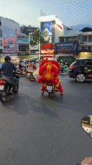 Lion dancer rides motorcycle through Vietnam city traffic