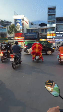 Lion dancer rides motorcycle through Vietnam city traffic