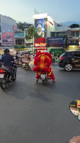 Lion dancer rides motorcycle through Vietnam city traffic