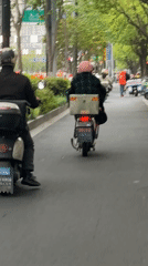 Scooter riders navigate tree-lined Shanghai street during overcast morning