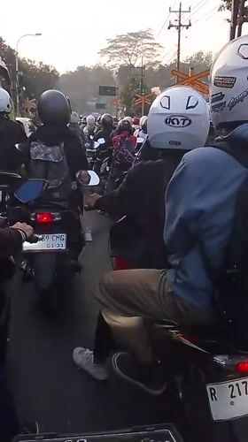 Motorcycle traffic stacks up at a Pasirmuncang railway crossing