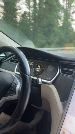 Tesla interior at 94 mph, driver smiling at camera