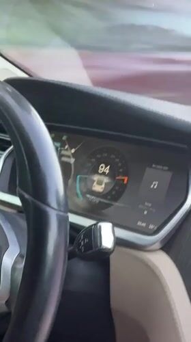 Tesla interior at 94 mph, driver smiling at camera