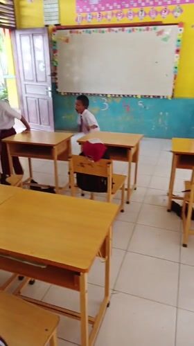 Boys play on classroom desks in Simpangjaya school