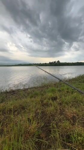 Angler fishes at lake under overcast skies in Bulgaria