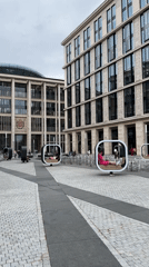 Public square with modern buildings and seated pedestrians documented