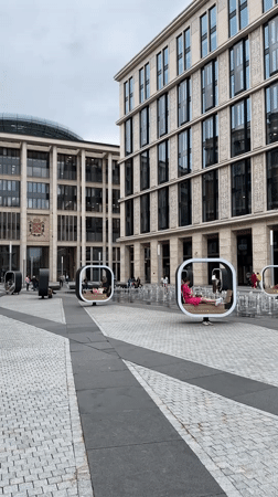 Public square with modern buildings and seated pedestrians documented