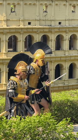 Roman costume performers pose by a miniature Colosseum replica