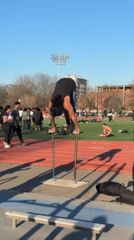 Man performs handstand split on school track parallel bars