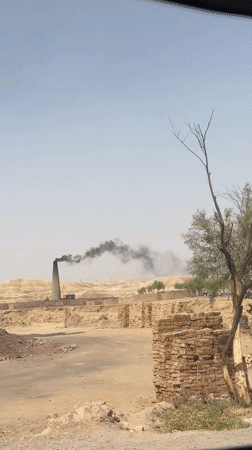 Brick kiln billowing black smoke in arid Kuchlak, Pakistan
