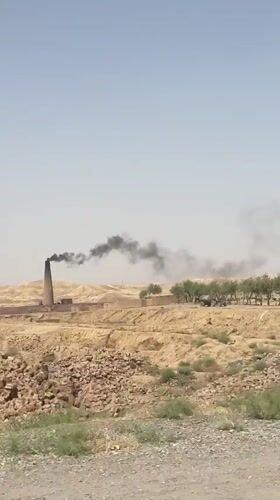 Brick kiln billowing black smoke in arid Kuchlak, Pakistan