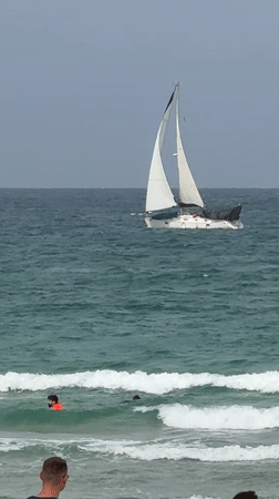 Overcast morning captured along Herzliya beach with sailboat offshore