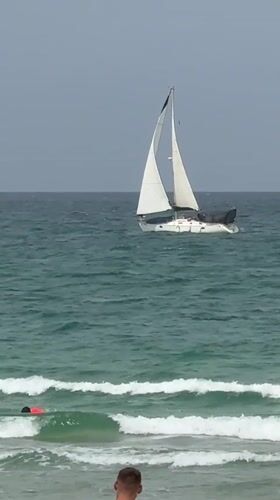 Overcast morning captured along Herzliya beach with sailboat offshore