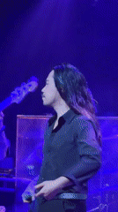 Four-piece band performs live indoor concert with colored stage lighting