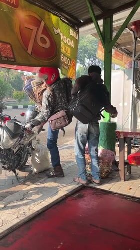 Busy morning motorcycle traffic through Candi, Indonesia at sunrise