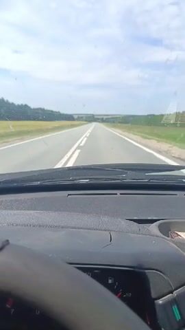 The video shows a first-person perspective from inside a vehicle driving down a paved road. The road is flanked by fields of yellow and green crops. The sky is cloudy, but sunlight is visible. The dashboard of the vehicle is in the foreground, with a steering wheel on the left. The speedometer shows a speed of approximately 140. The time stamp indicates the video was recorded on June 20, 2023, between 00:00 and 00:04.