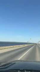 Car travels sunny road near water in Chaikovsky, Russia