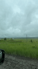 Vehicle travels muddy rural road in Russian countryside