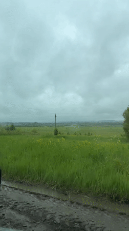 Vehicle travels muddy rural road in Russian countryside