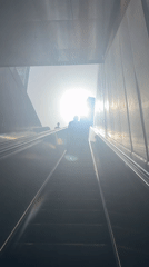 Morning commuters ride escalator into bright sunlight in Ramat Gan