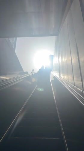 Morning commuters ride escalator into bright sunlight in Ramat Gan