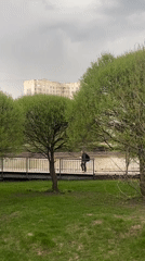 Person crosses bridge in Moscow park on cloudy afternoon
