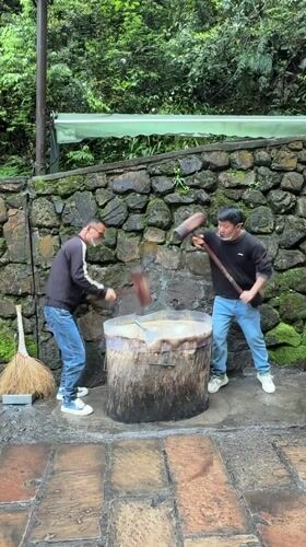 Men pound substance with mallets in traditional preparation, Xiehe
