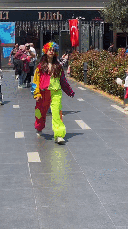 Clown-costumed person walks past children playing in Çekmeköy