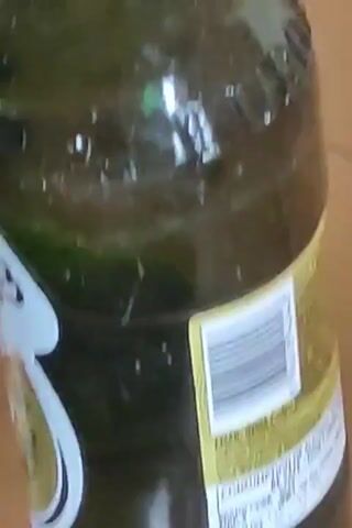 The video displays two green glass bottles. The bottle on the left is larger and has a label with the word "COPENHAGEN" and "TUBORG" printed on it. The bottle on the right is smaller and has a label with the text "1880" and "STRONG". The bottles appear to be on a wooden surface. The lighting is dim, suggesting an indoor environment.