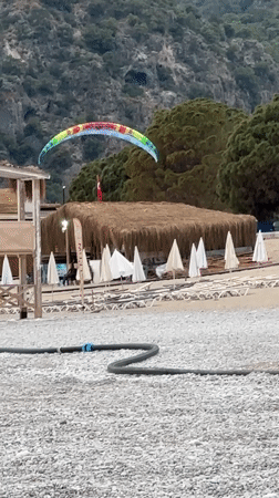 Paraglider performs tricks over Fethiye beach in Turkey