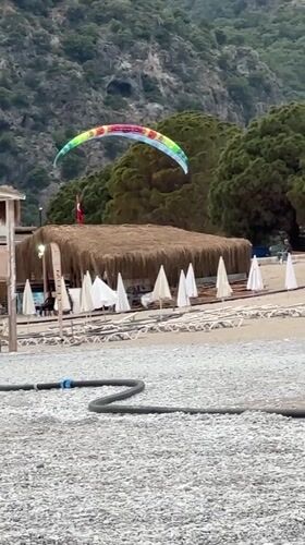 Paraglider performs tricks over Fethiye beach in Turkey