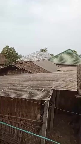 THE VIDEO SHOWS AN EXTERNAL VIEW OF SEVERAL ROOFS OF DIFFERENT BUILDINGS. THE ROOFS ARE CONSTRUCTED FROM VARIOUS MATERIALS INCLUDING TILES, CORRUGATED METAL, AND SOME UNIDENTIFIED MATERIAL. ONE ROOF APPEARS TO BE UNDER CONSTRUCTION WITH A METAL FRAMEWORK VISIBLE. THE BUILDINGS ARE MADE OF BRICK AND WOOD, AND THERE ARE TREES IN THE BACKGROUND. THE SKY IS OVERCAST.