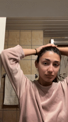 Woman arranges hair in bathroom during morning routine, Montenegro