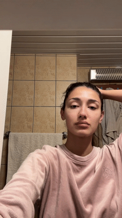 Woman arranges hair in bathroom during morning routine, Montenegro