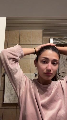 Woman arranges hair in bathroom during morning routine, Montenegro