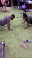 Two men perform facing push-ups on gym turf