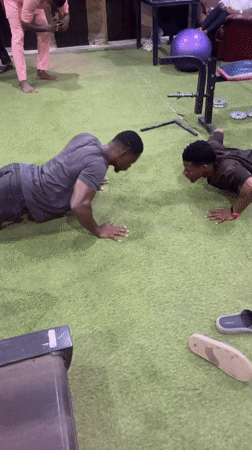 Two men perform facing push-ups on gym turf
