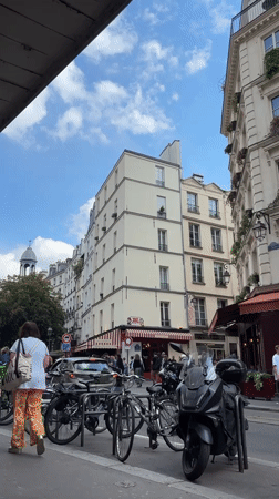Man walks past parked vehicles on Paris street