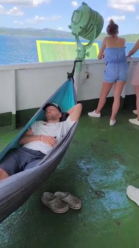 Man sleeps in hammock on boat deck near Gerung