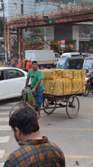 Cyclist hauls cardboard boxes through busy Dhaka intersection