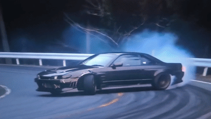 Sports cars drifting smoky corners on winding rural roads.