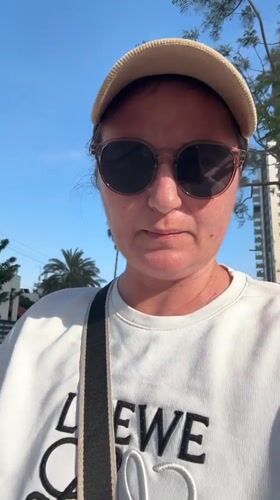 Woman in Loewe sweatshirt rides electric scooter in Netanya