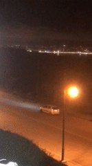 White car loses traction on nighttime urban street