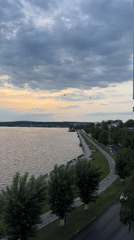 Birds fly over Votkinsk Reservoir waterfront during cloudy afternoon